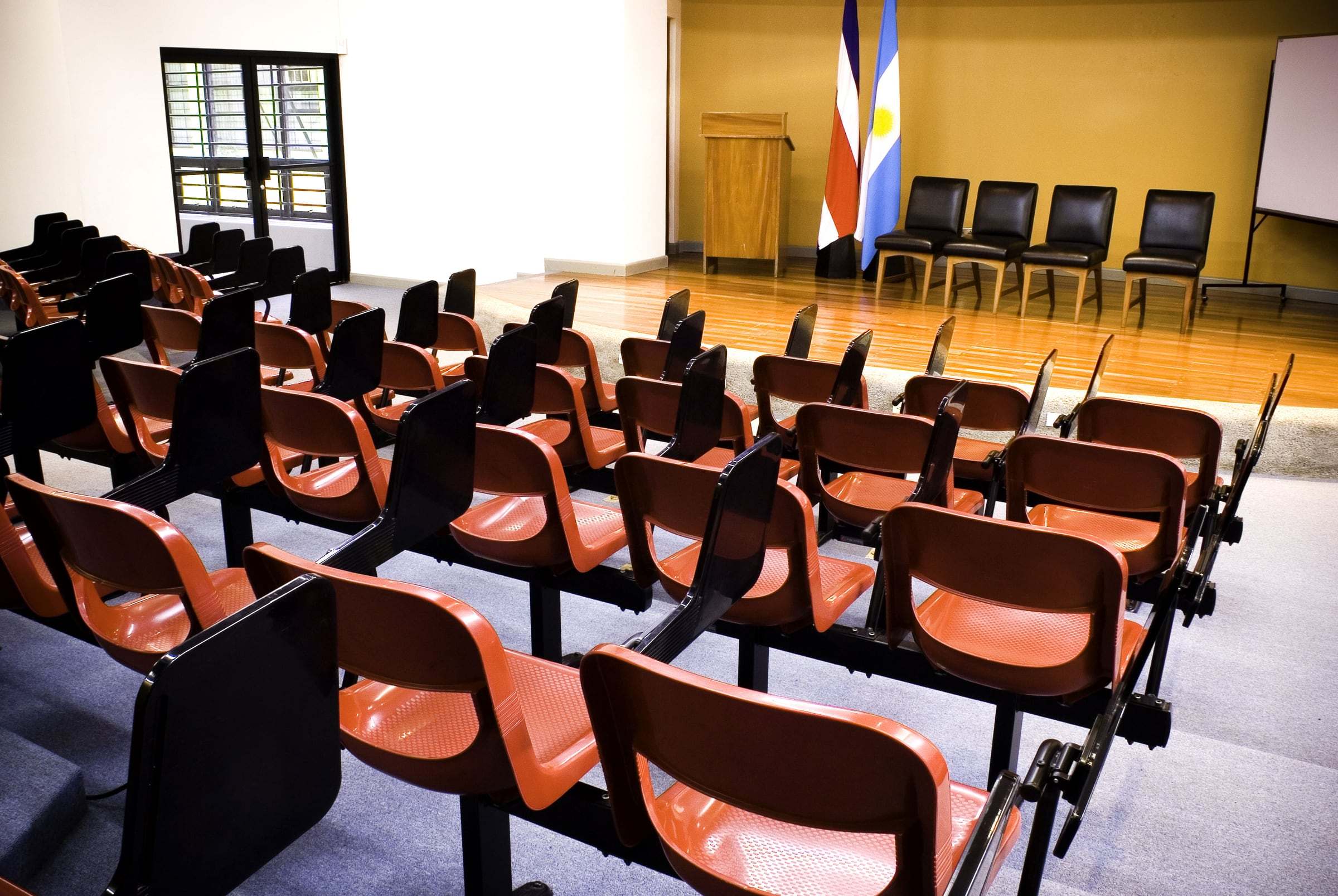 Auditorio de la Facultad de Agronomía de la UCR con butacas anaranjadas y piso de madera