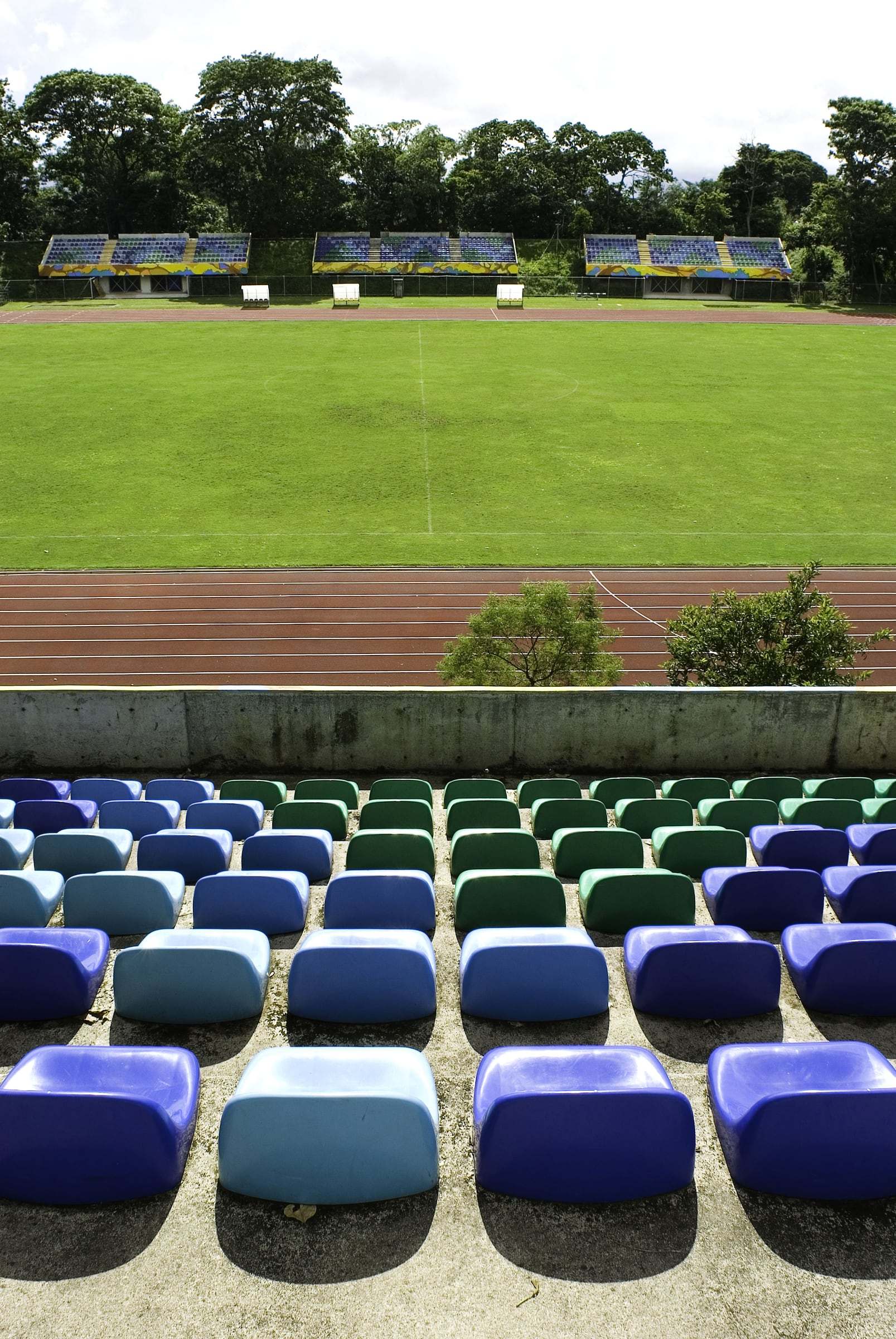 Butacas azules y verdes en la gradería frente a la cancha del Estadio Ecológico de la UCR