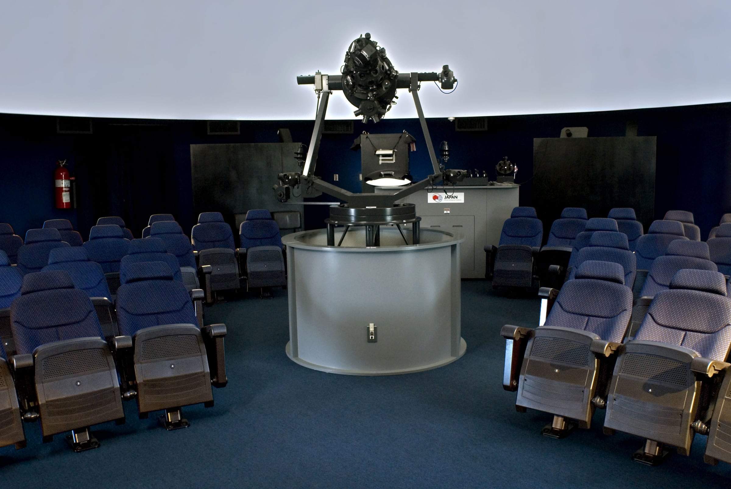 Sala del Planetario de la UCR con butacas grises alrededor del proyector